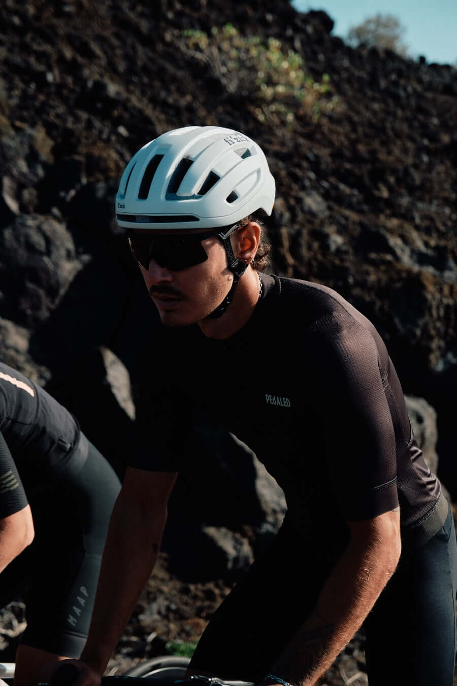 Kask Rowerowy FIZIK Kyros White na kolarzu, podczas dynamicznej jazdy na rowerze górskim.