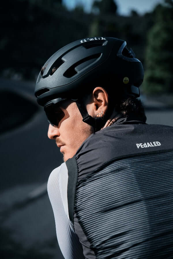 Kask rowerowy FIZIK Kyros Black na kolarzu, zapewniający bezpieczeństwo i komfort w trakcie jazdy.